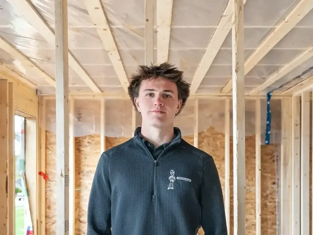 Brennan Schofield, owner of Wildawbren Holdings, standing inside a freshly framed home wearing a Wildawbren branded fleece