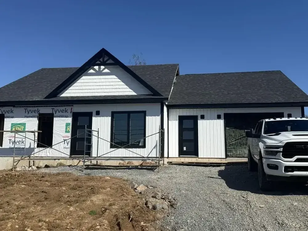 A Wildawbren new build, a white board-and-batten home with a covered porch and a truck parked on the freshly graded driveway